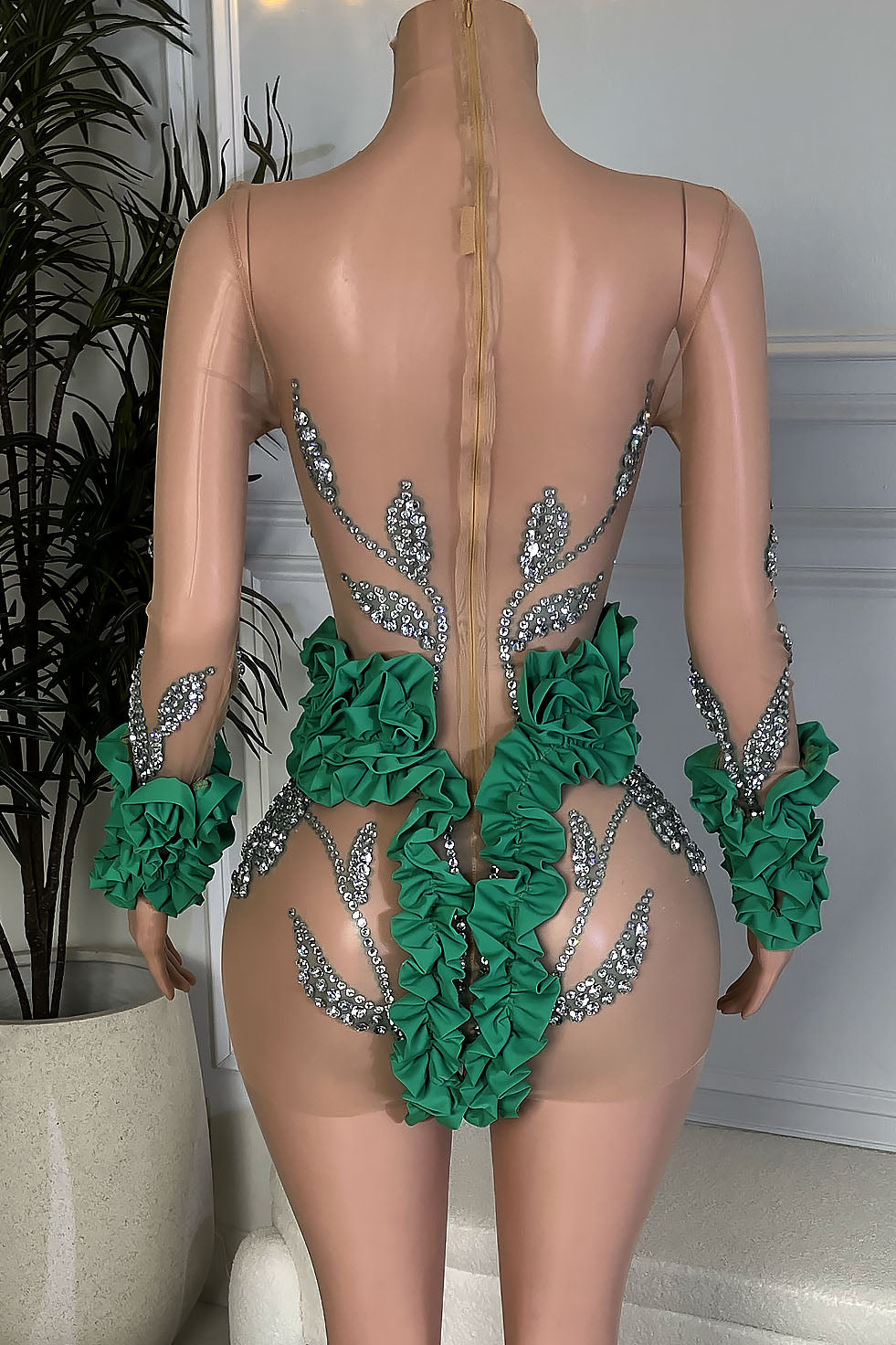Back view of nude illusion rhinestone mini dress with green ruffle trim and long sleeves, Amekana.