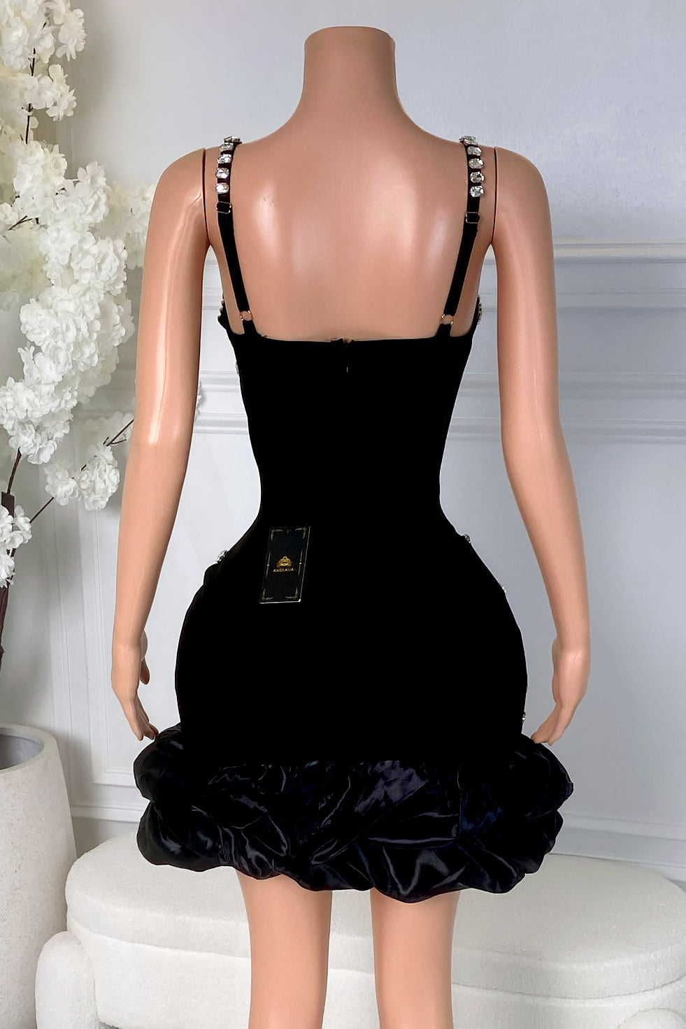 Back view of black rhinestone mini dress with smooth black back, zipper closure, rhinestone straps, and bubble hem