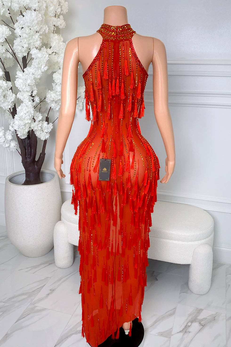 Back view of red tassel rhinestone maxi dress with sheer mesh, rhinestone detailing, tassel fringe, high neckline, and back zipper closure