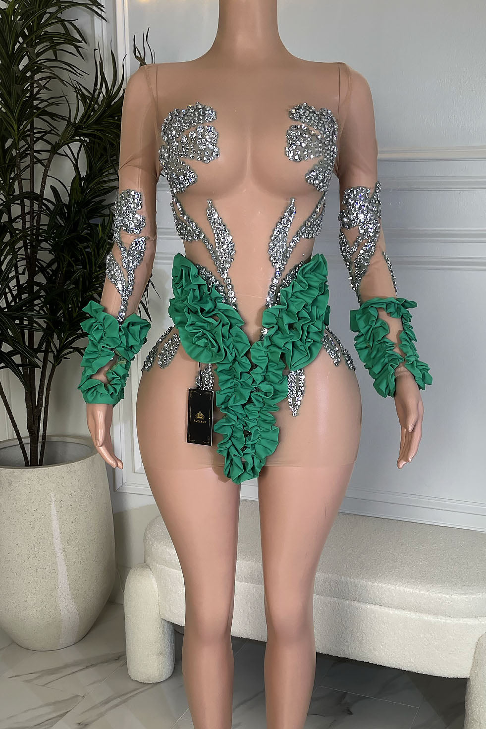 Nude illusion mesh mini dress with silver rhinestones and emerald green ruffle waist detail, Amekana.
