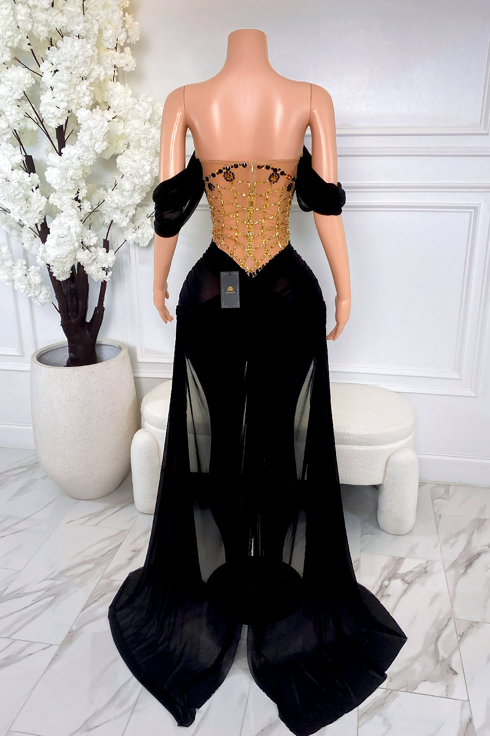 Back view of black and gold rhinestone dress with illusion beaded back and long black sheer train