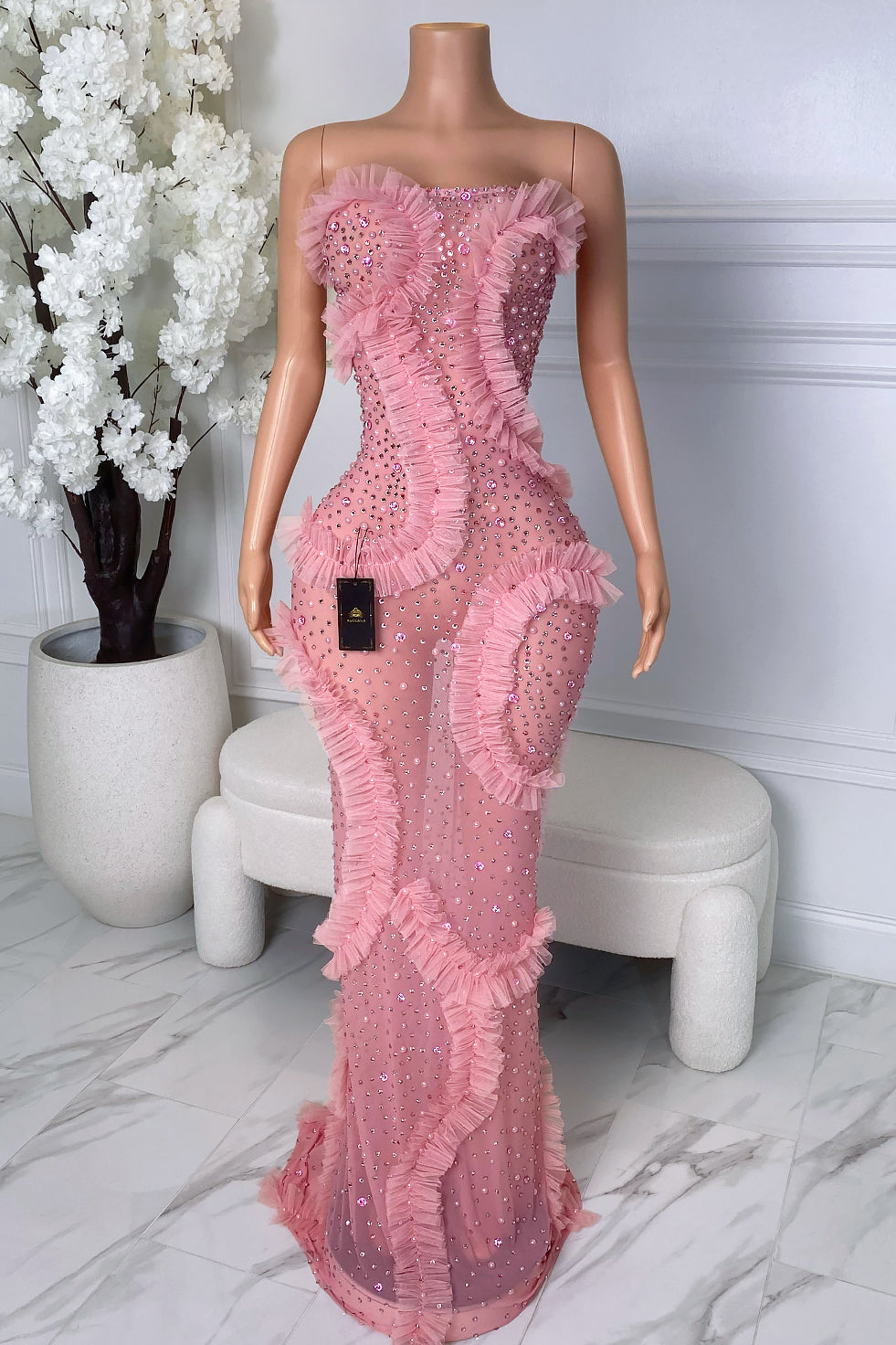 Front view of pink rhinestone maxi dress with strapless neckline and ruffle details