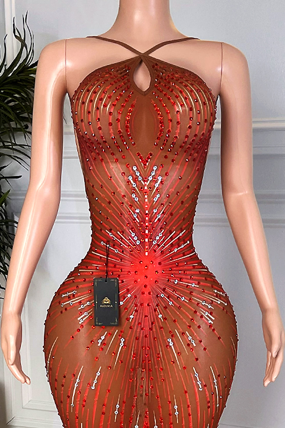 Close-up halter neckline and keyhole cutout on nude illusion mesh dress with red rhinestone burst pattern