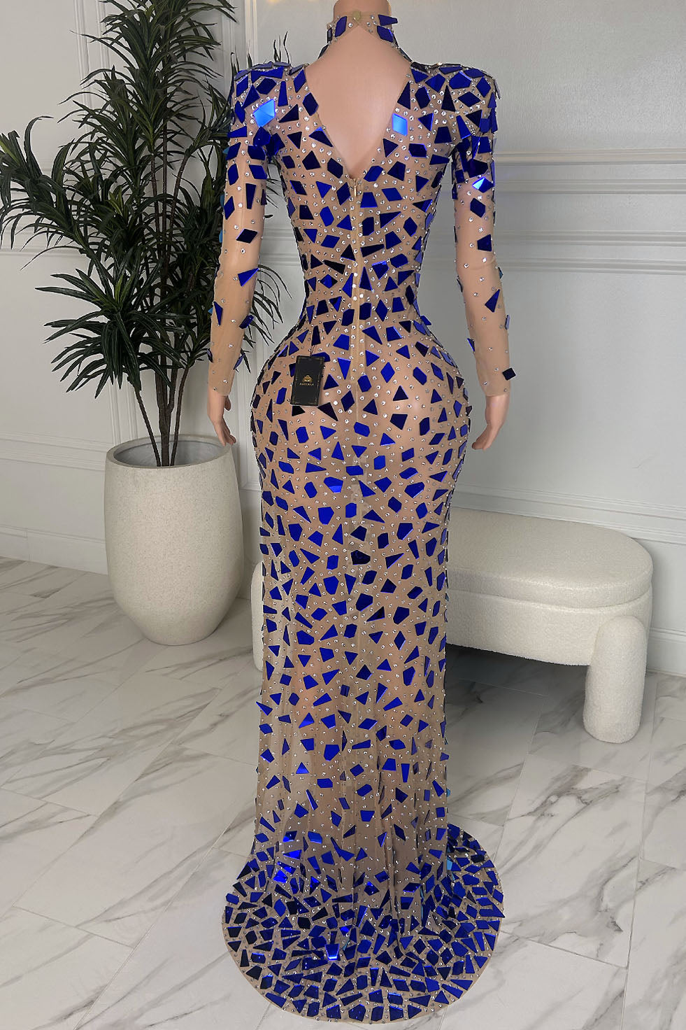 Back view of nude mesh maxi gown with cobalt mirror shard appliqués and rhinestones, featuring a deep V back and floor length silhouette