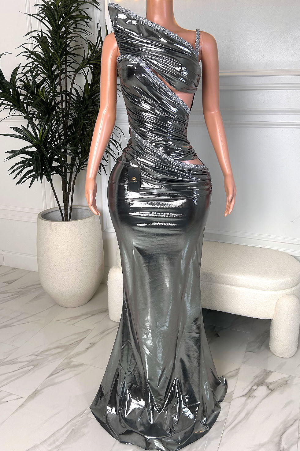 Back view of silver metallic mermaid gown with glossy liquid finish, thin straps, and fitted silhouette with flared hem