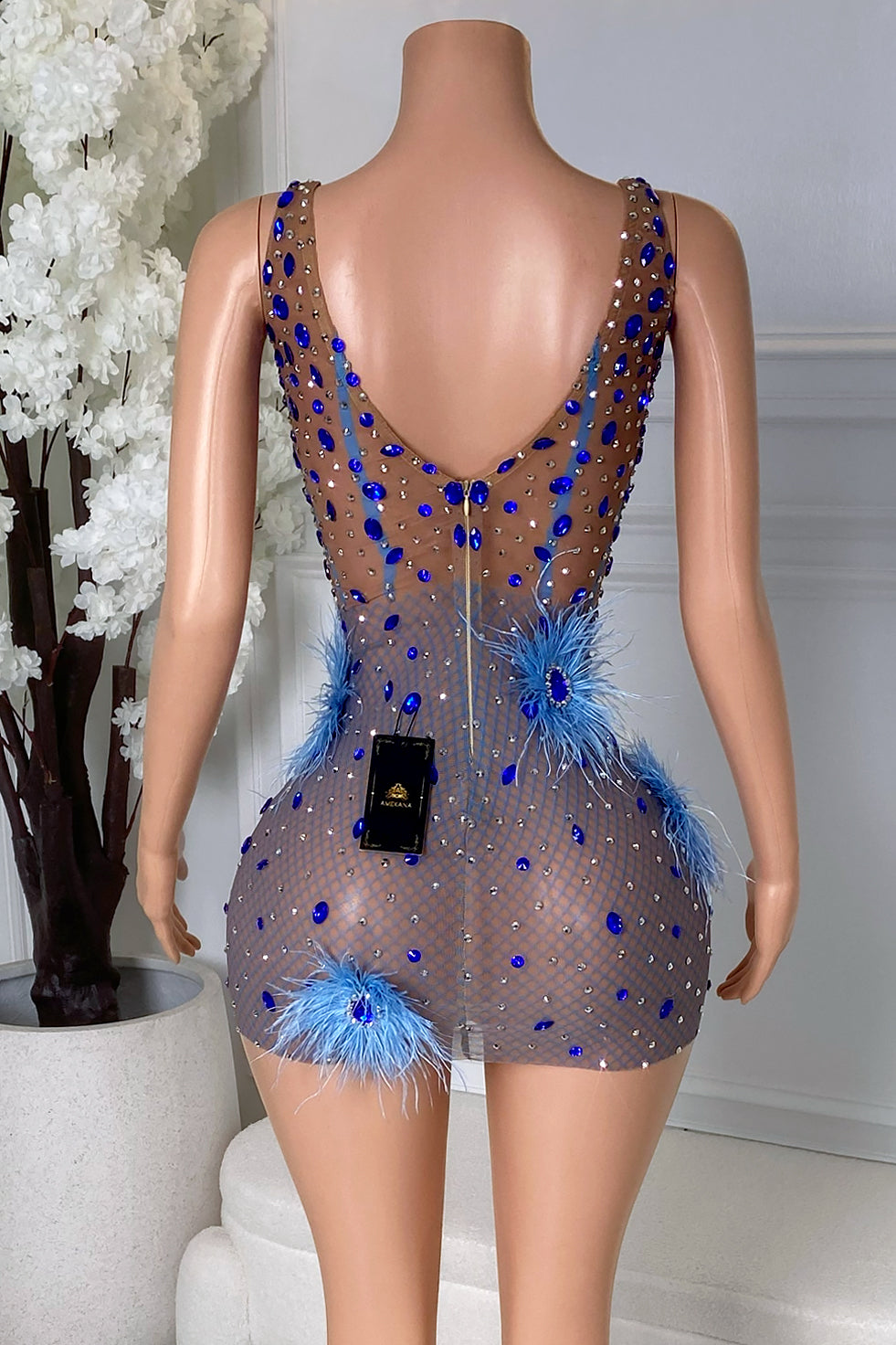 Back view of the Yacinia Blue Feather Mini Dress showing the sheer nude mesh design, blue rhinestone embellishments, feather details, and zipper closure.