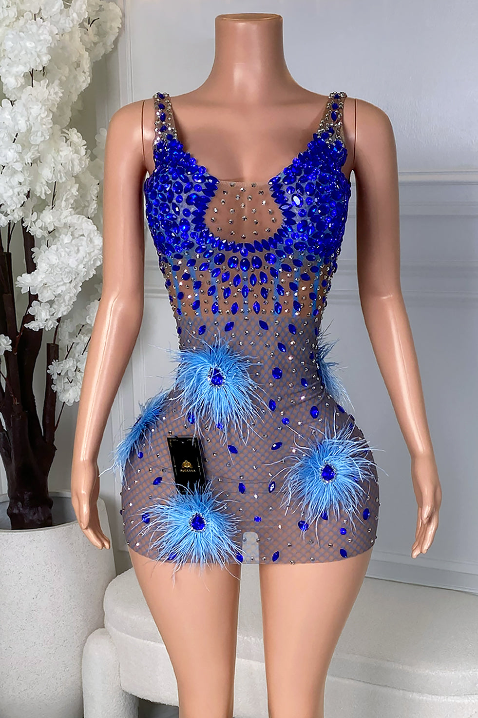 Front view of a Blue Feather Mini Dress featuring nude mesh, royal blue rhinestones, silver crystal accents, and blue feather details.