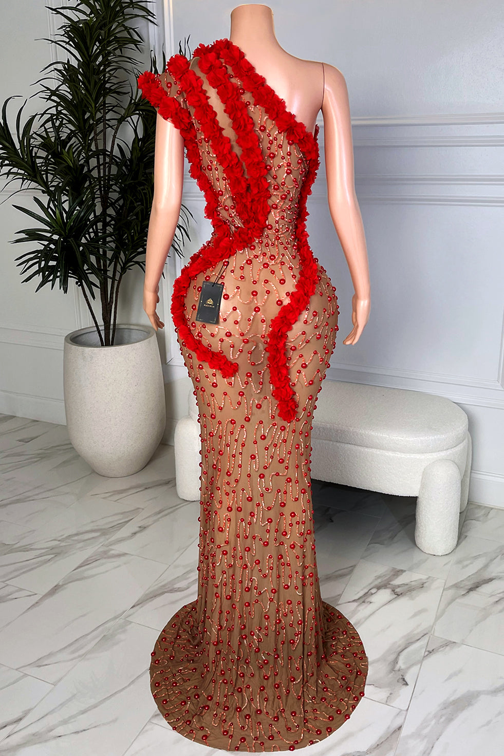 Asymmetrical one shoulder nude mesh gown with red bead embellishment and red floral trim, back view