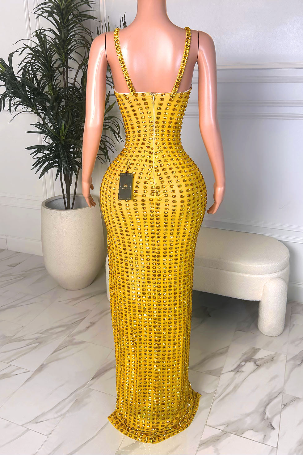 Back view of a yellow embellished evening gown with slim straps, deep scoop back, back zipper closure, and floor-length silhouette