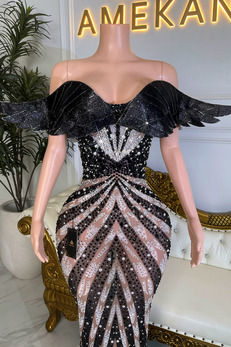 Close up of Kimber black rhinestone gown bodice with off shoulder wing sleeves and glittery crystal pattern on nude mesh