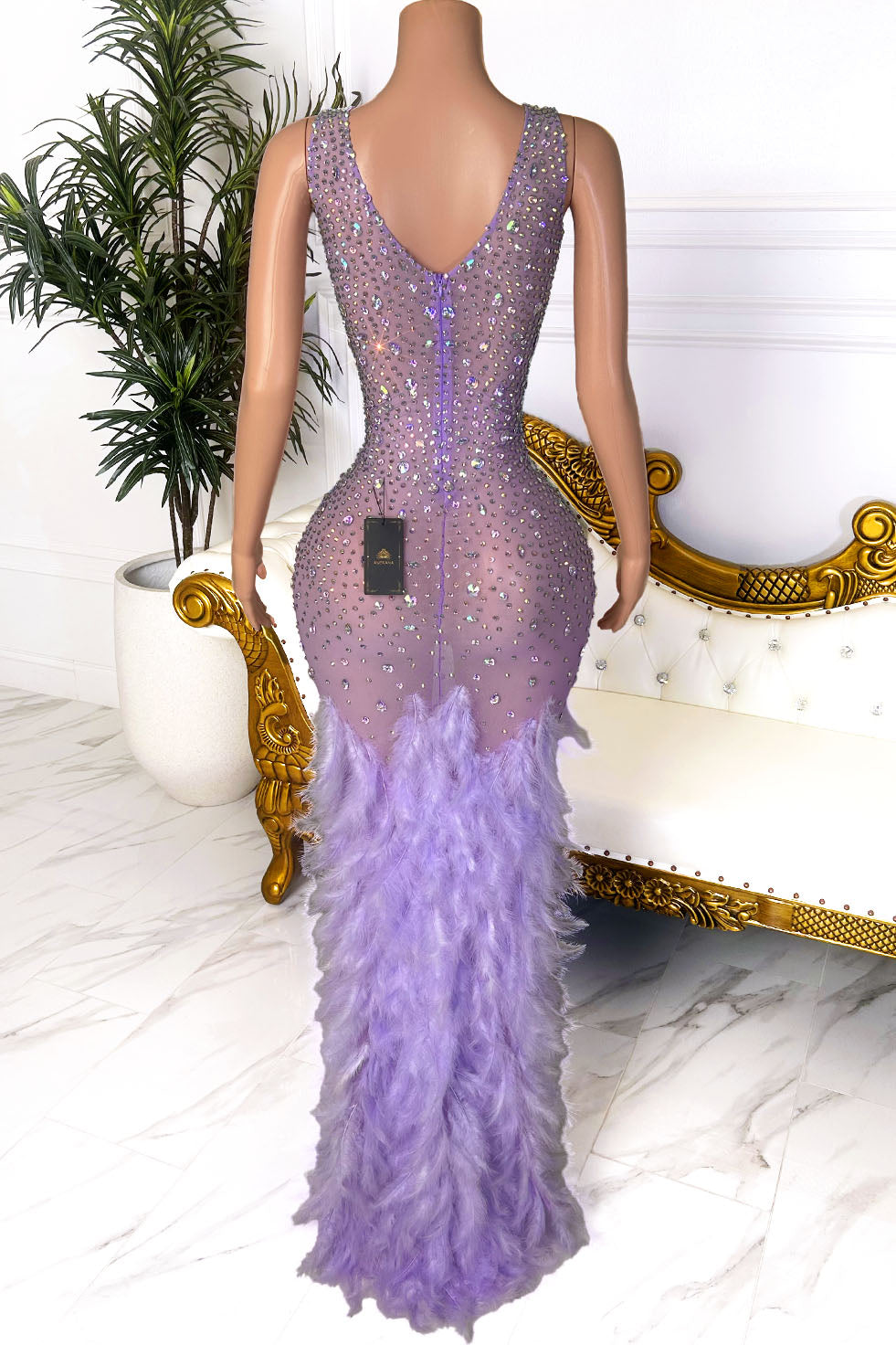 Back view of lavender crystal embellished maxi gown with sleeveless design, fitted silhouette, and feather bottom detail.