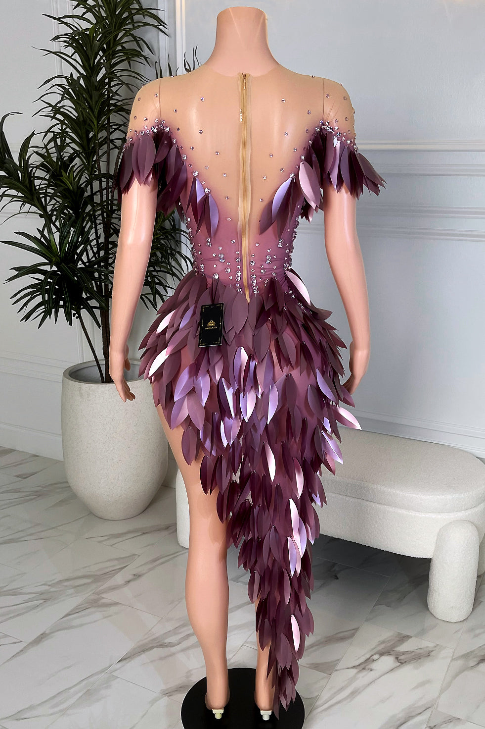 Back view of plum petal nude illusion mini dress with cascading asymmetrical appliqué detail and rhinestone embellishments by Amekana.