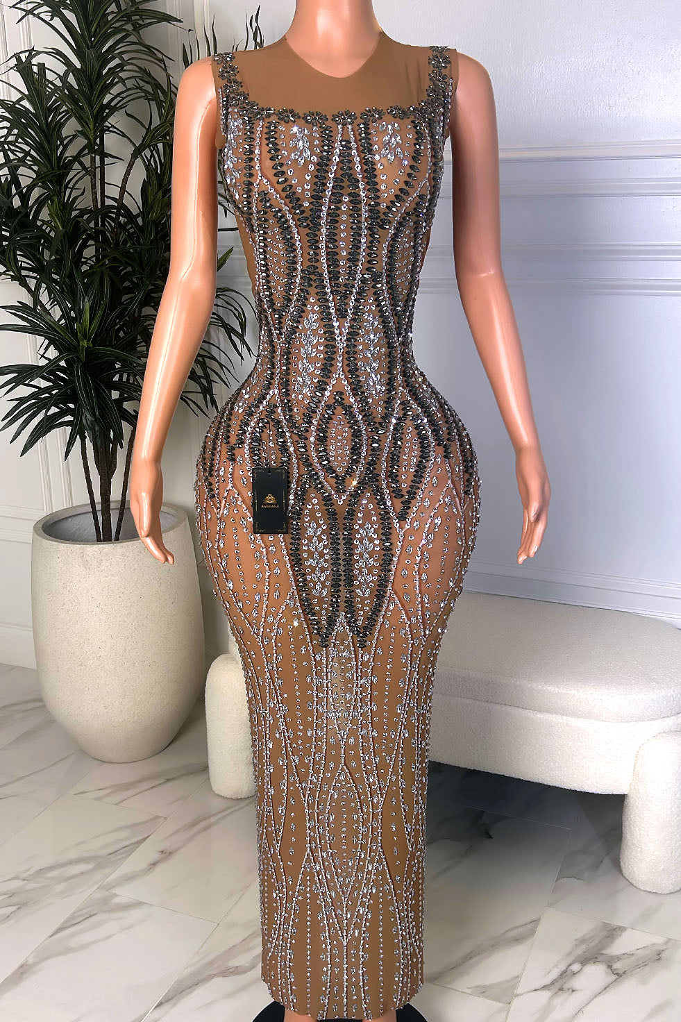 Front view of a nude illusion floor-length gown with black and silver crystal embellishment, sleeveless shoulders, and a sculpted fitted silhouette