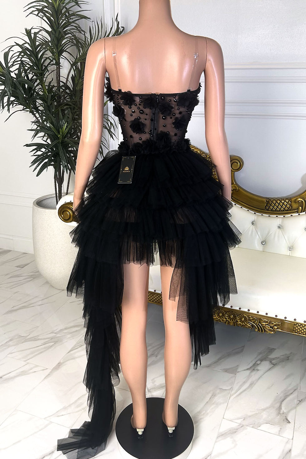 Back view of a black mini dress with sheer embellished bodice, clear straps, and cascading high-low tulle skirt