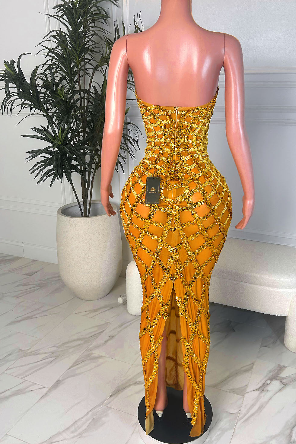 Back view of a red metallic one shoulder mermaid gown showing the fitted silhouette and glossy floor length train