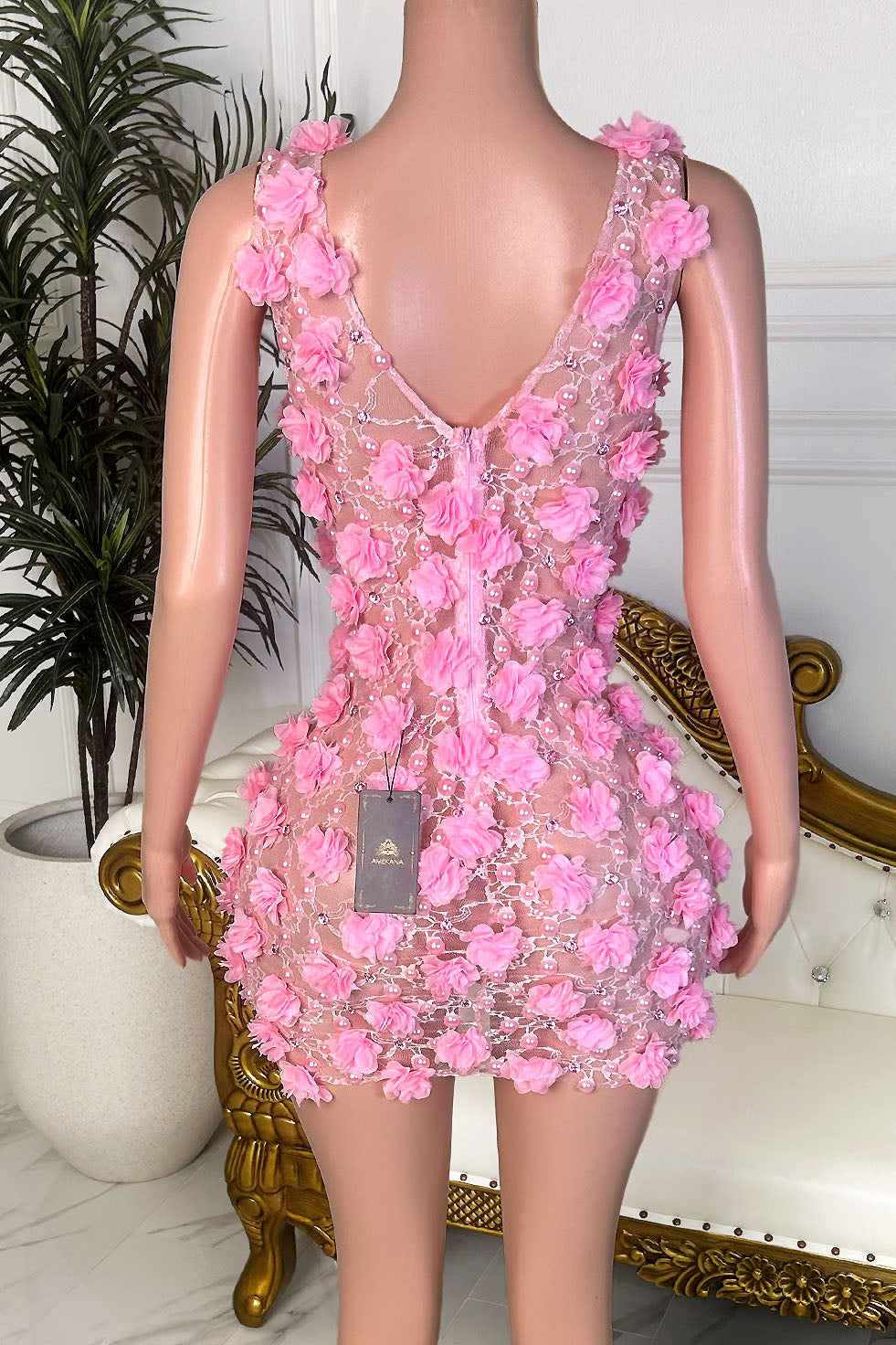 Back view of a pink floral mini dress with allover rosette appliqué, nude illusion base, and deep V back