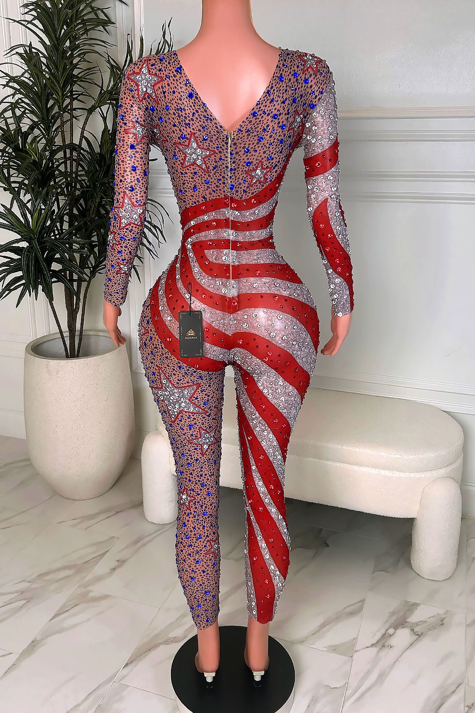 star-spangled-stunner-rhinestone-jumpsuit-front-amekana.jpg
Alt text: Front view of a nude illusion rhinestone jumpsuit with bold red and silver stripes, star motifs, and blue crystal detailing for a patriotic glam look