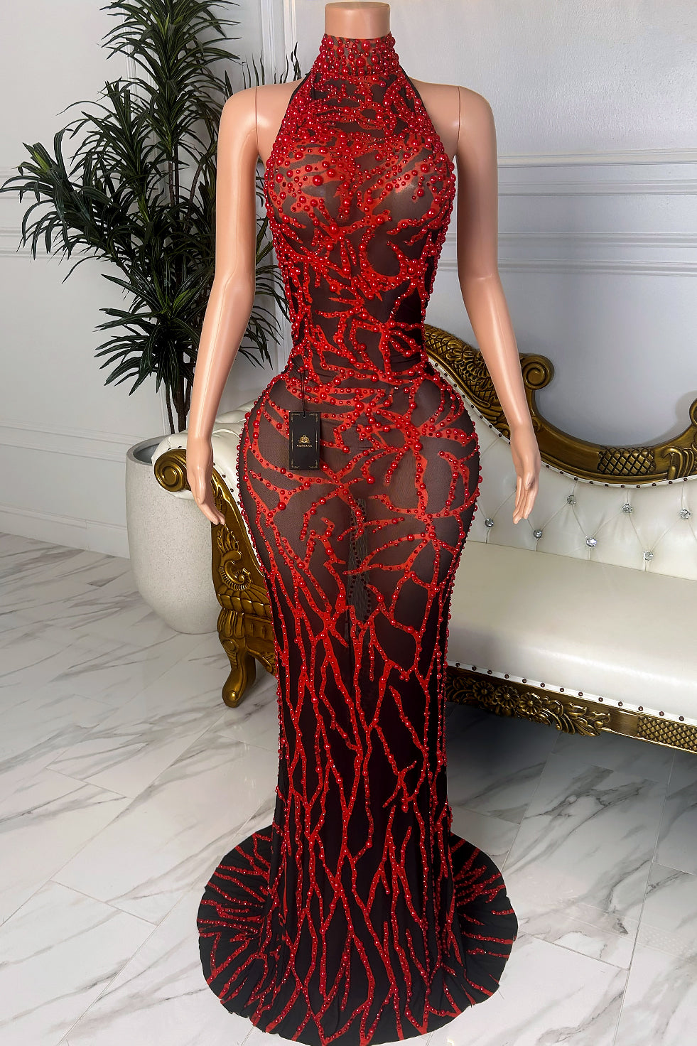 Front view of a black sheer mesh halter dress with red beaded floral embellishments, fitted floor-length silhouette, illusion details, and trailing hem.