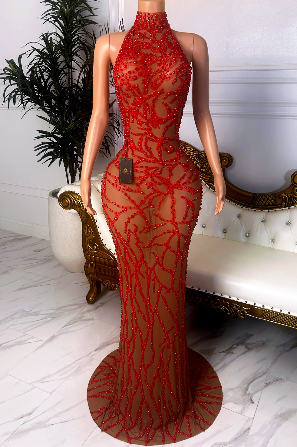 Front view of a nude sheer mesh halter dress with red beaded floral embellishments, fitted floor-length silhouette, illusion details, and trailing hem