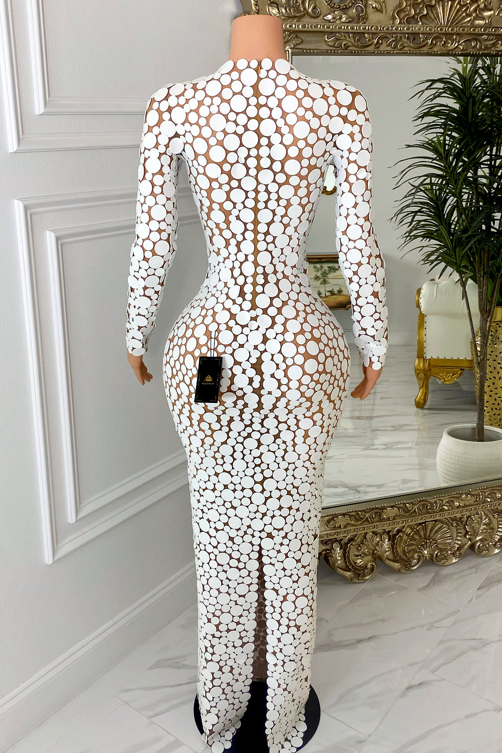 Front view of nude illusion mesh maxi dress with white circle appliqué, long sleeves, high neckline, and body-hugging fit