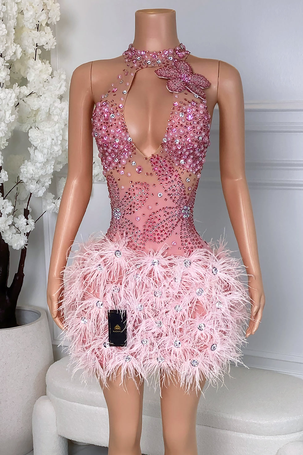 Front view of pink feather rhinestone mini dress with sheer mesh bodice and butterfly detail
