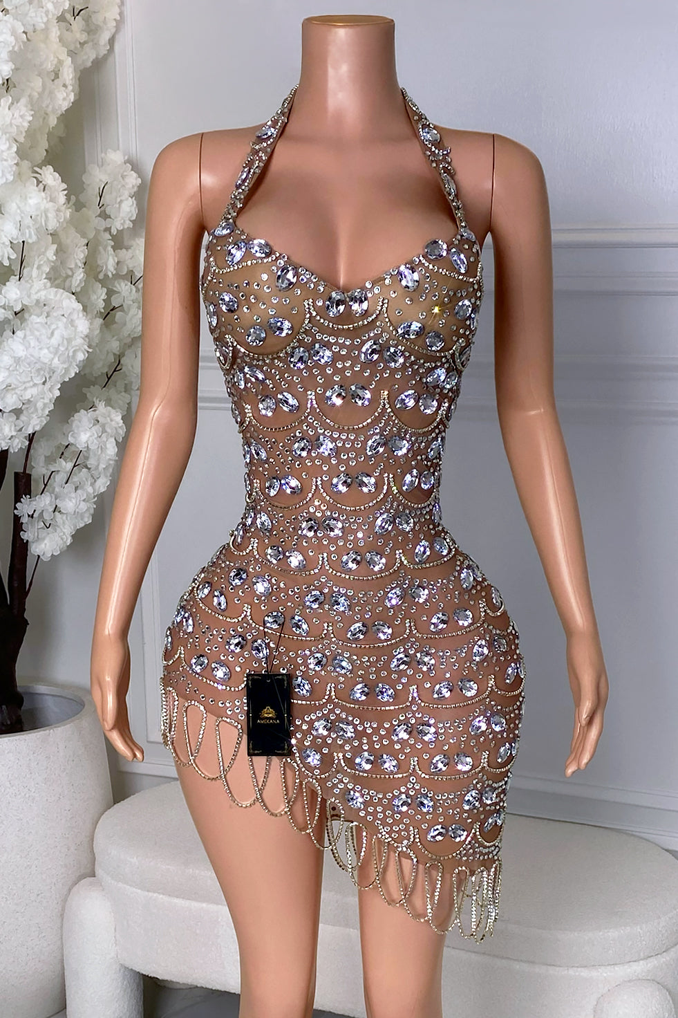 Front view of the Yacinia Crystal Mini Dress featuring a halter neckline, nude illusion base, silver crystal embellishments, oversized rhinestones, and asymmetrical chain hem.