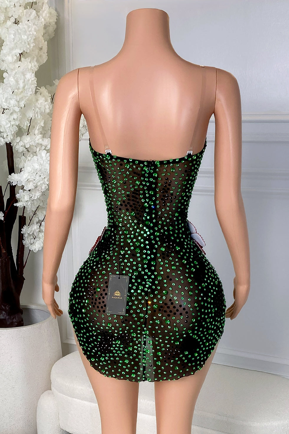 Back view of the Yacinia Emerald Bloom Mini Dress featuring green rhinestones, black floral detailing, clear straps, and a back zipper closure.