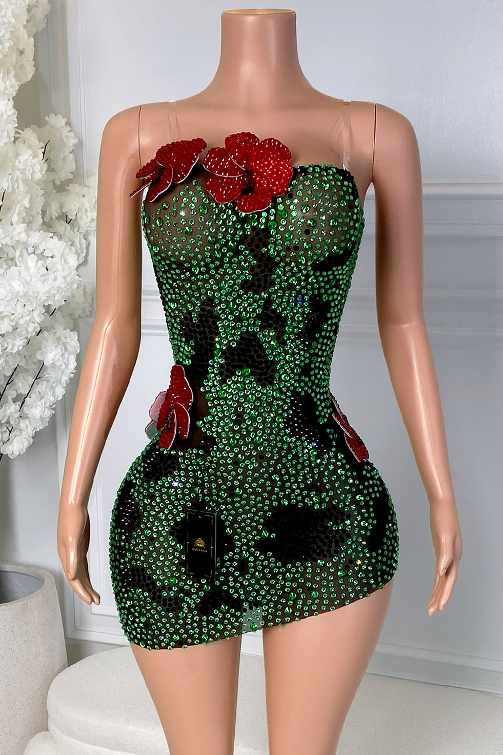 Front view of the Yacinia Emerald Bloom Mini Dress featuring a nude mesh base, green rhinestones, black floral pattern, and red 3D flower accents