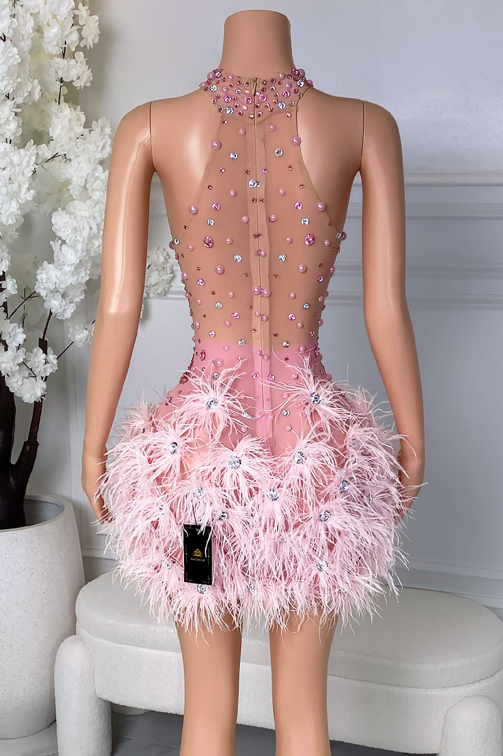 Back view of pink feather rhinestone mini dress with high neckline, zipper closure, and crystal accents
